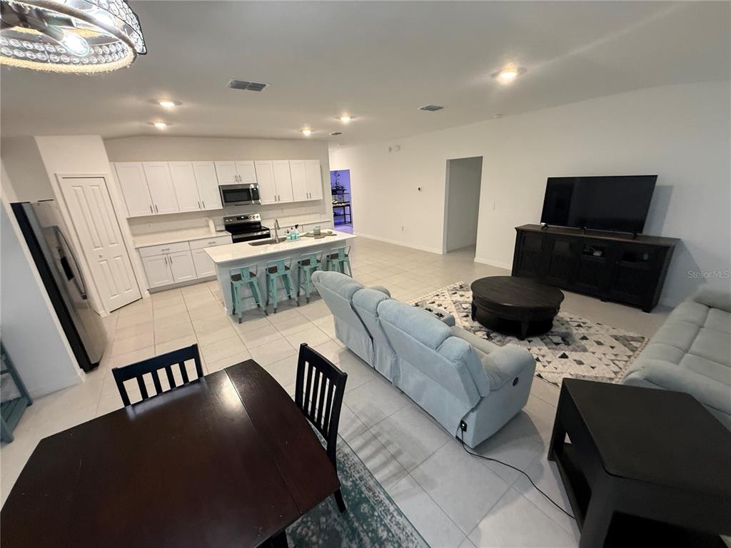 An open-concept kitchen and living area features white cabinetry, a central island, and tile flooring — 13038 CALCITE BLUE AVENUE, WIMAUMA, FL