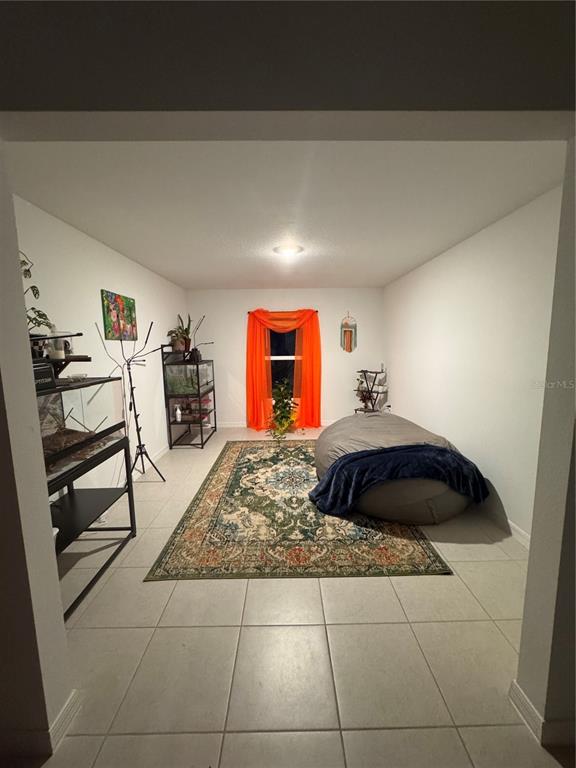 A room with tile flooring, a large area rug, a beanbag chair, and two reptile enclosures — 13038 CALCITE BLUE AVENUE, WIMAUMA, FL