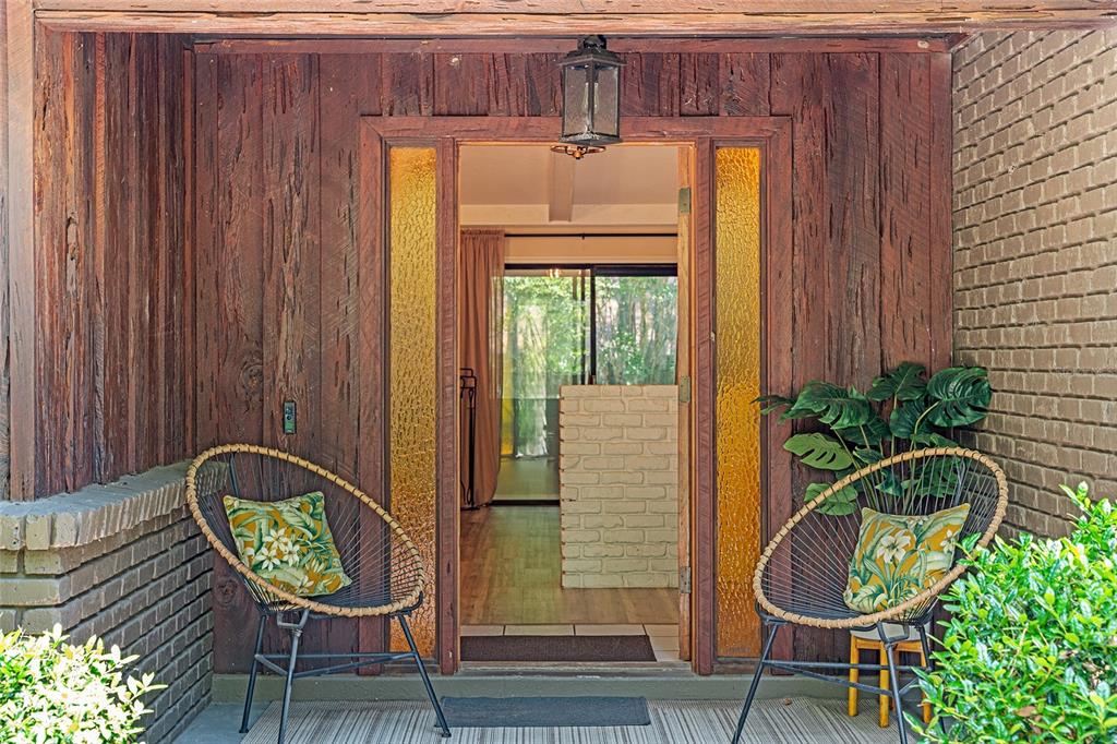 A front porch features two wire chairs, wood siding, and a doorway with amber sidelights — 8101 NW 46TH STREET, OCALA, FL