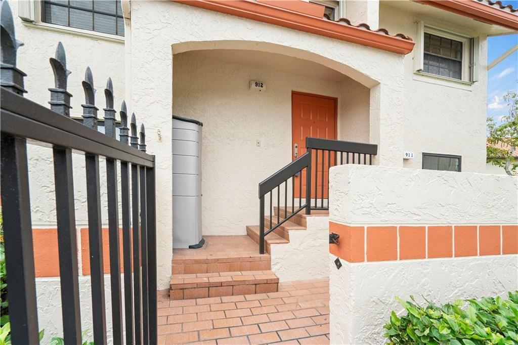 An exterior view of a residential building entrance with a brick walkway and stairs — 912 Congressional Way, Deerfield Beach FL 33442, DEERFIELD BEACH, FL