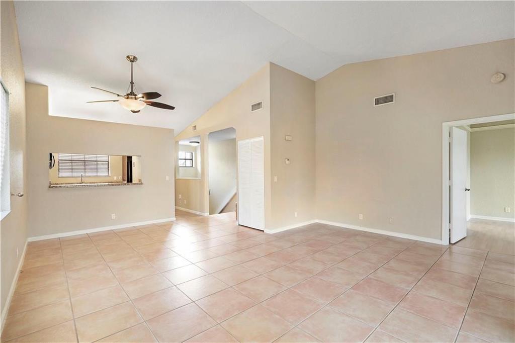 A spacious living area features beige tile flooring, vaulted ceilings, and a ceiling fan — 912 Congressional Way, Deerfield Beach FL 33442, DEERFIELD BEACH, FL