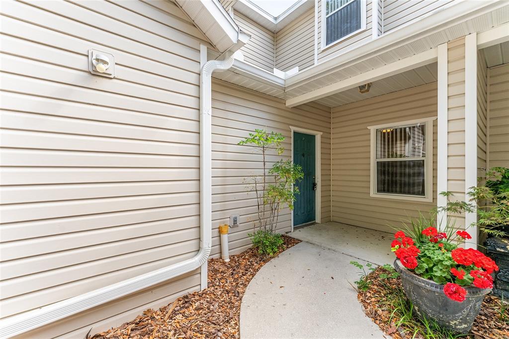 A beige-sided home exterior features a concrete walkway leading to a blue front door — 4700 SW ARCHER ROAD UNIT 13, GAINESVILLE, FL