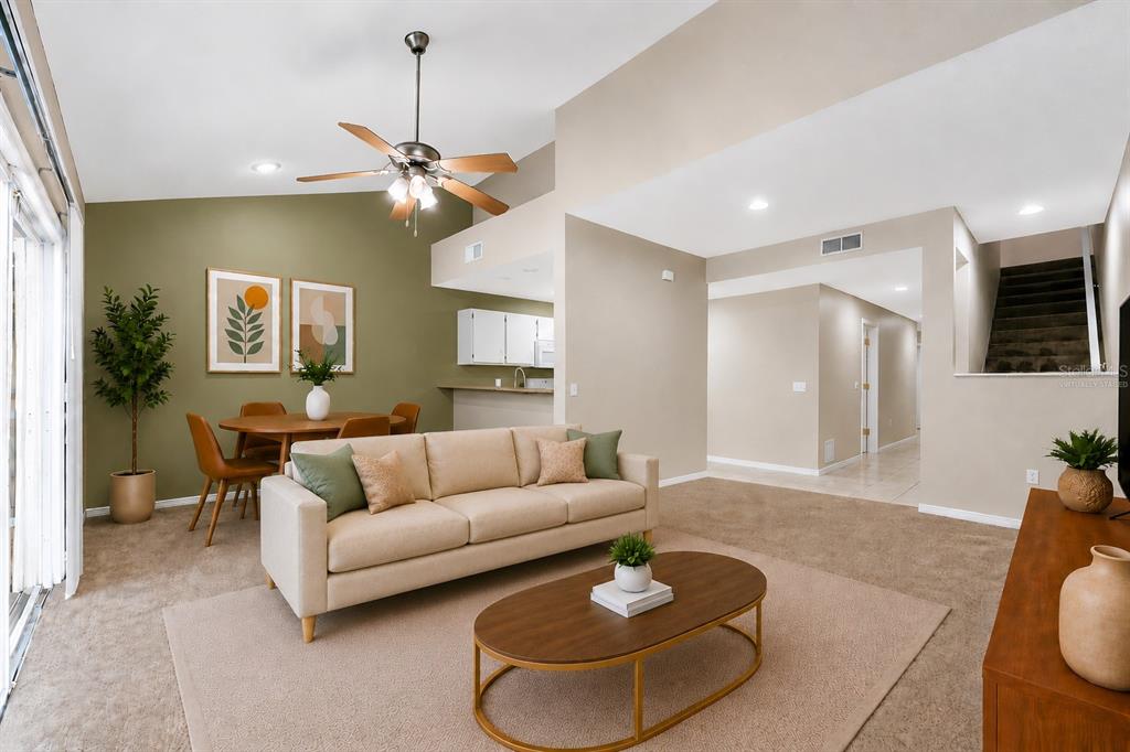 A living room with beige carpet, a tan sofa, a coffee table, and a dining area — 4700 SW ARCHER ROAD UNIT 13, GAINESVILLE, FL
