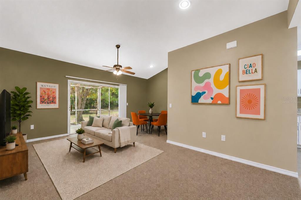 A living room with beige carpet, olive green walls, a sofa, and a dining set — 4700 SW ARCHER ROAD UNIT 13, GAINESVILLE, FL