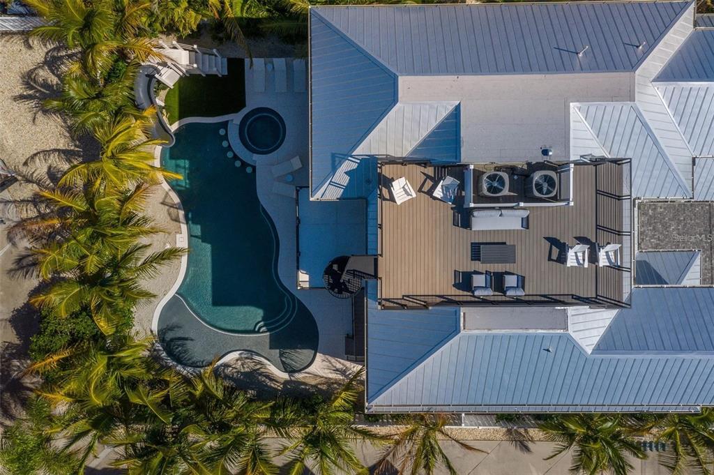 An aerial view shows a house with a rooftop deck, swimming pool, and palm trees — 119 MCKINLEY DRIVE, SARASOTA, FL