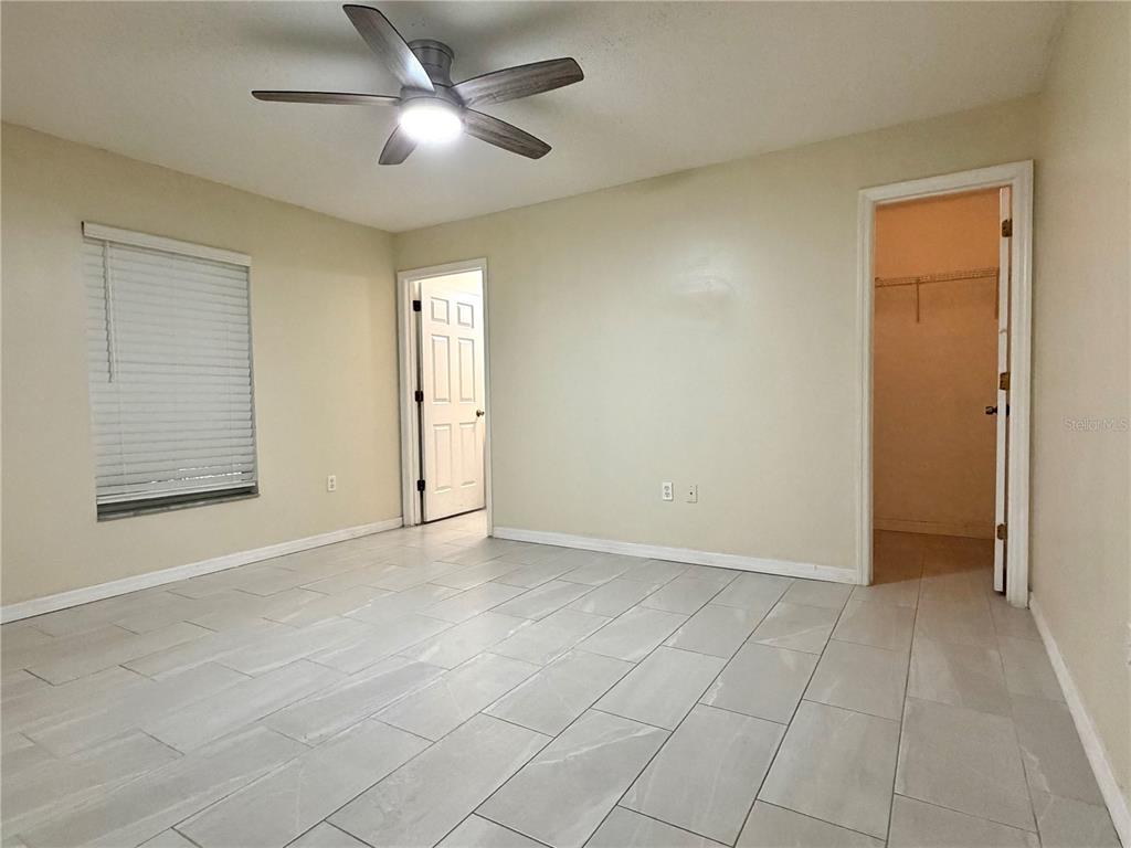 An empty bedroom features light-colored tile flooring, a ceiling fan, and two doorways — 1172 JADE EAST, KISSIMMEE, FL