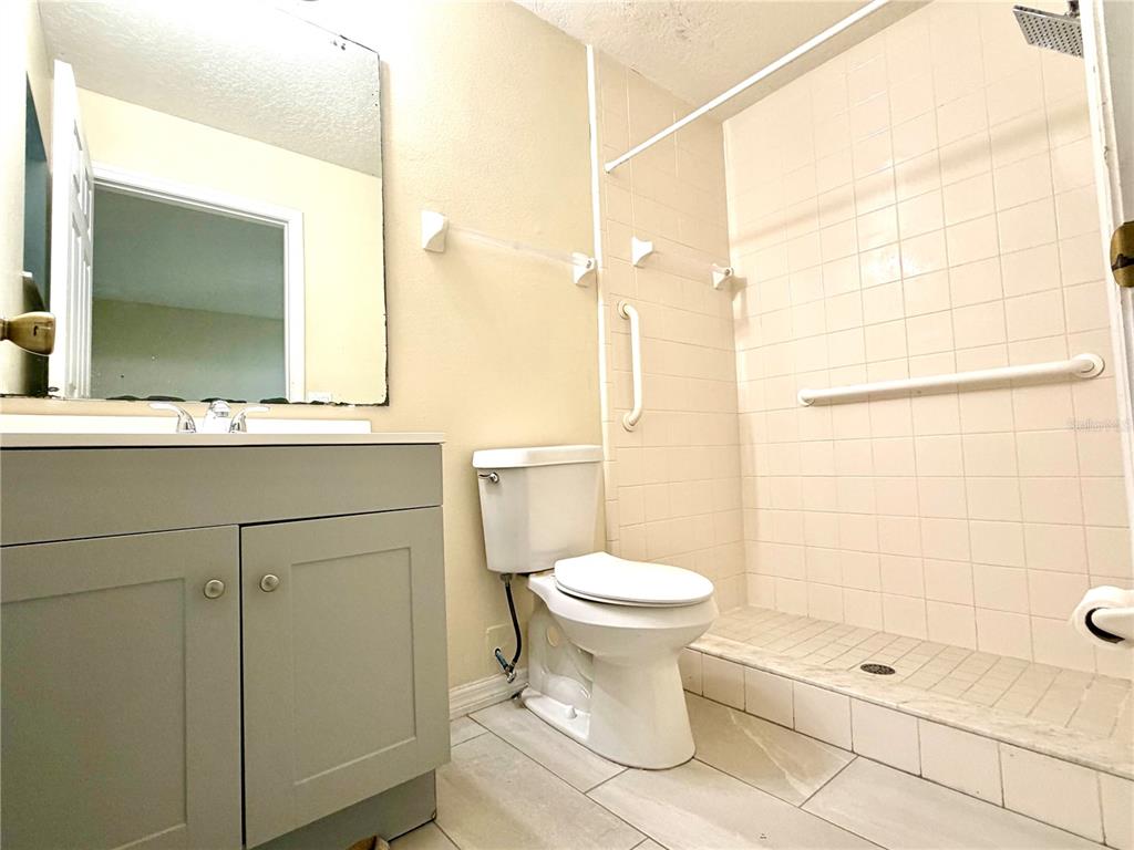 A bathroom features a gray vanity, a white toilet, and a tiled walk-in shower — 1172 JADE EAST, KISSIMMEE, FL