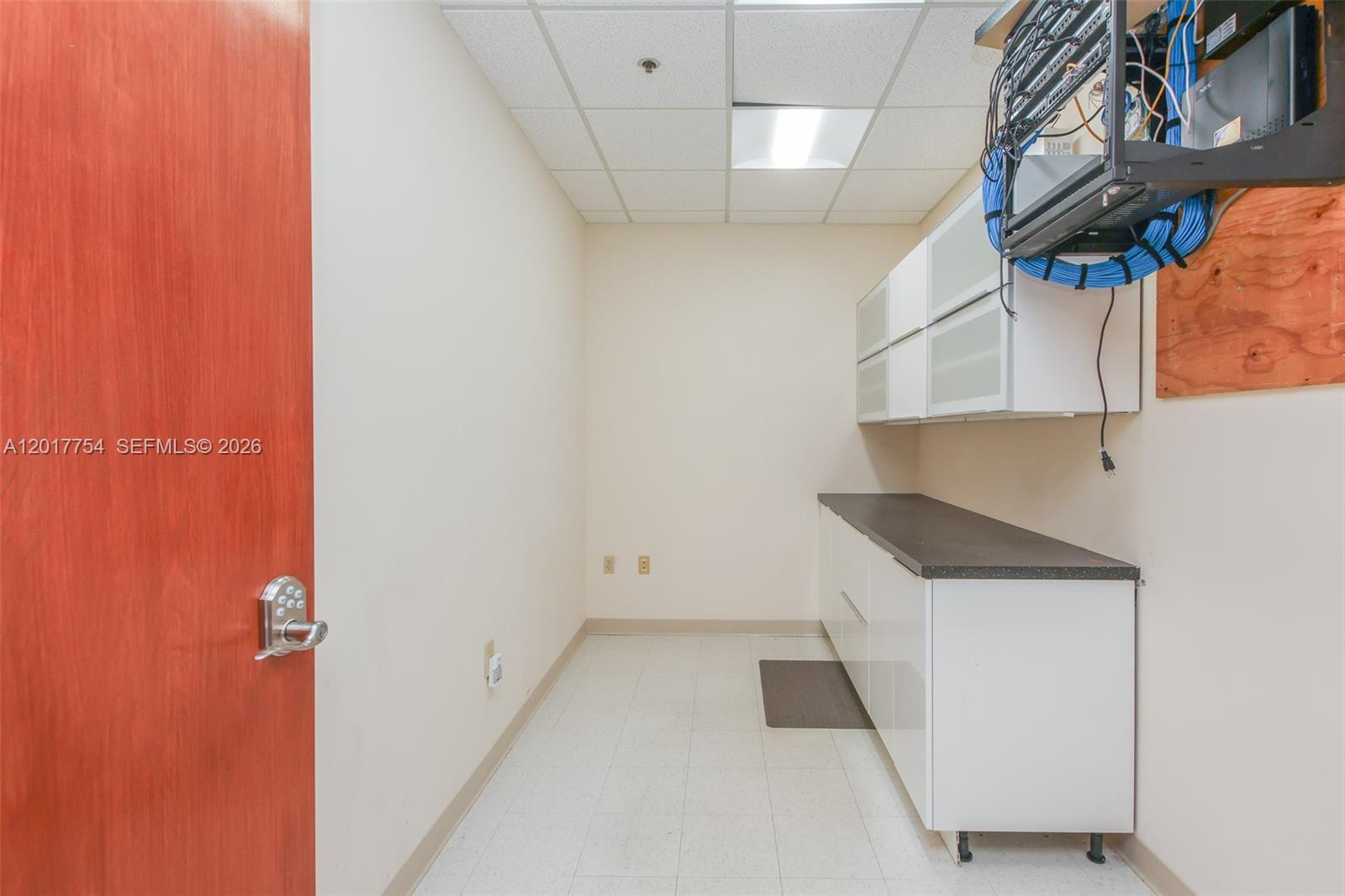 A small utility room features white cabinets, a dark countertop, and wall-mounted networking equipment — 1900 Glades Rd # 245, Boca Raton FL 33431, BOCA RATON, FL