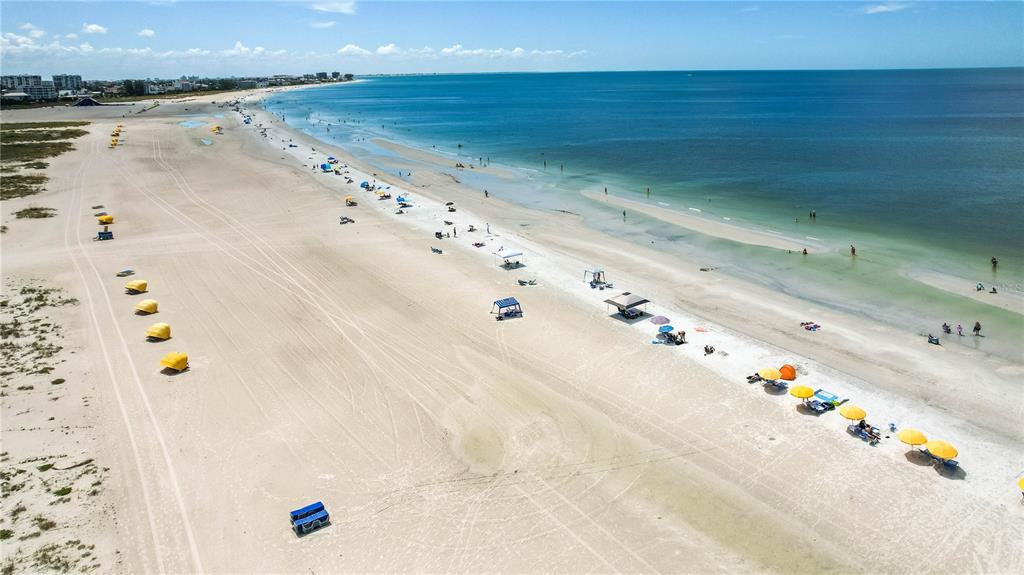 An aerial view of a sandy beach with colorful umbrellas and the ocean in the distance — 11605 GULF BOULEVARD UNIT 503, TREASURE ISLAND, FL