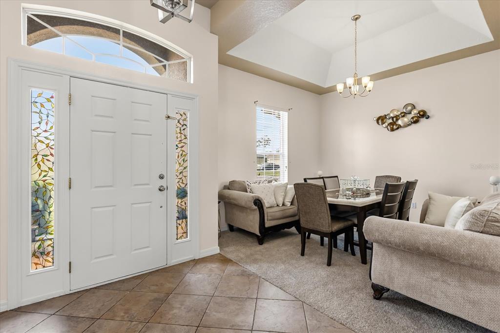 A dining area with a tray ceiling, tiled entryway, and a front door with sidelights — 3878 WOOD THRUSH DRIVE, KISSIMMEE, FL