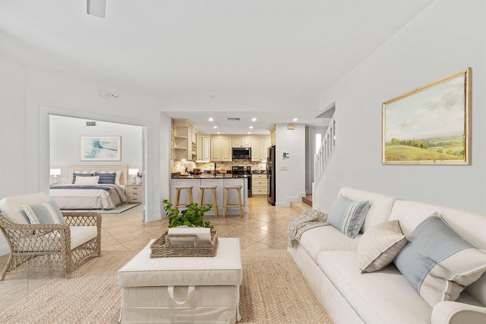 A living room with a white sofa and wicker chair opens to a kitchen and bedroom — 2703 N Fairway Dr Drive N, Jupiter FL 33477, JUPITER, FL
