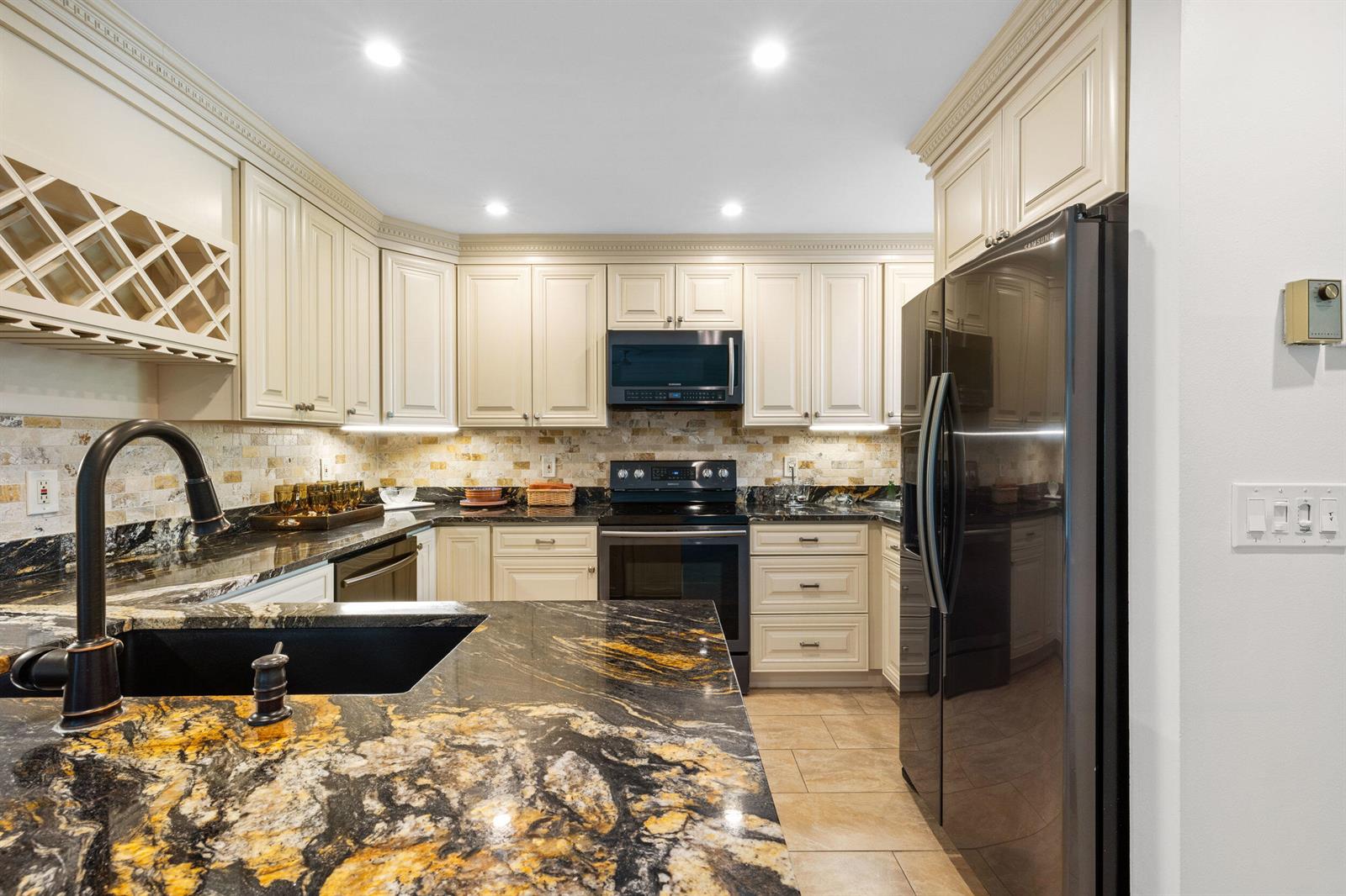 A kitchen features cream cabinets, black granite countertops, a black sink, and black appliances — 2703 N Fairway Dr Drive N, Jupiter FL 33477, JUPITER, FL