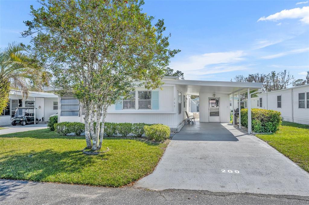 A single-story mobile home features a white exterior, a carport, and a front lawn — 269 KELOU COURT, LEESBURG, FL