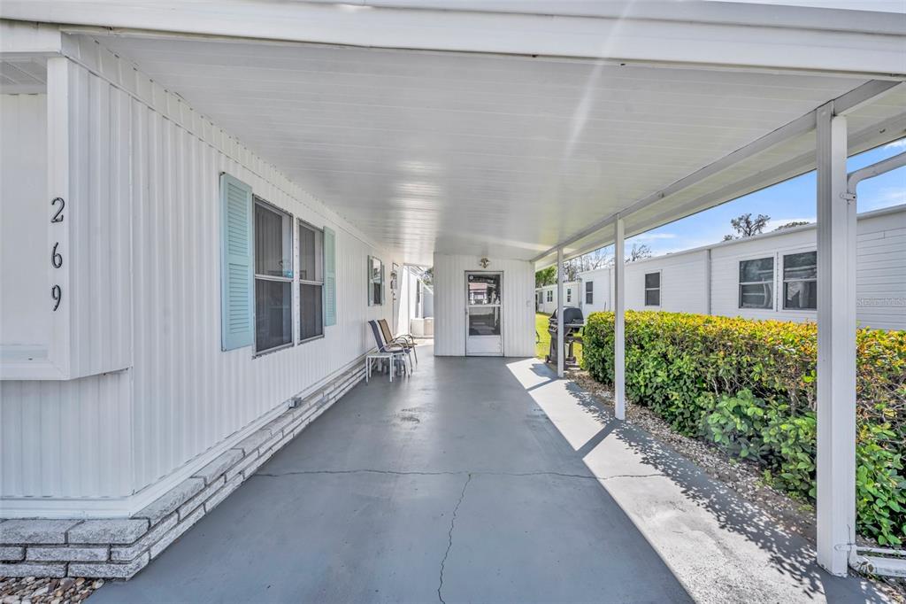 A covered carport with a concrete floor leads to the entrance of a mobile home — 269 KELOU COURT, LEESBURG, FL