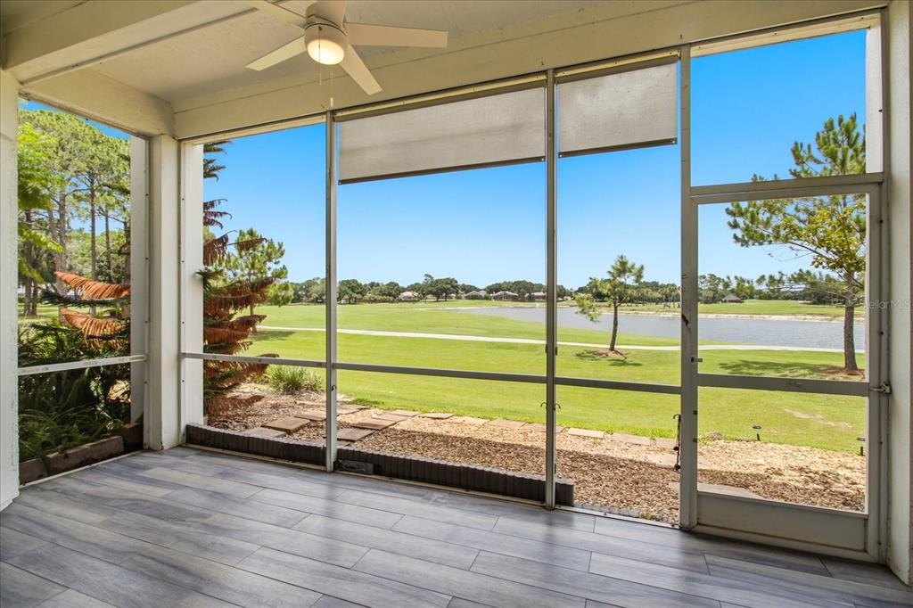 A screened-in porch with wood-look tile flooring overlooks a golf course and a pond — 459 HAMPTONCREST CIRCLE UNIT 103, LAKE MARY, FL