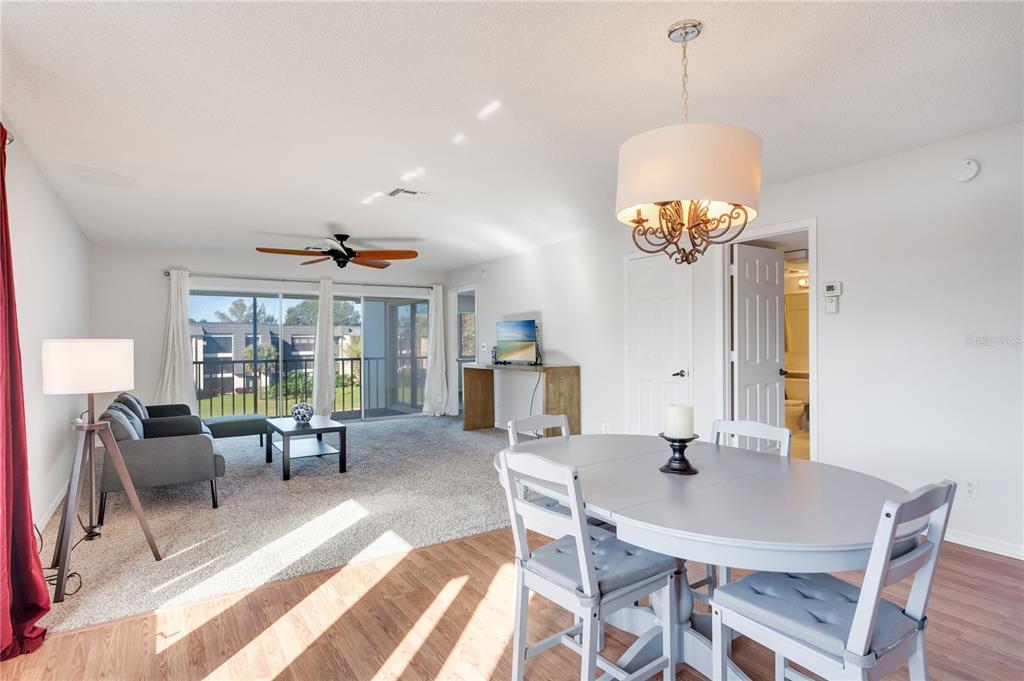 A dining area with a grey table and chairs transitions into a carpeted living room — 1645 SPOONBILL LANE UNIT C, NAPLES, FL