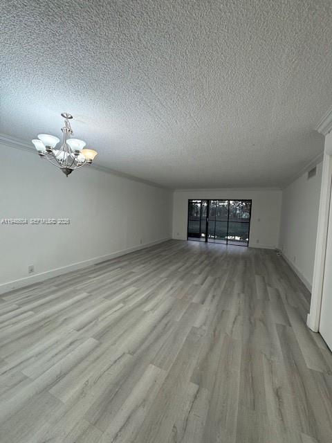 An empty room features light wood-look flooring, a textured ceiling, and a decorative chandelier — 321 Lakeview Dr # 105, Weston FL 33326, WESTON, FL