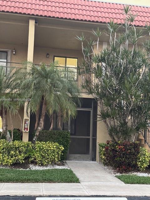 The exterior of a two-story building features a tan facade, palm trees, and a walkway — 321 Lakeview Dr # 105, Weston FL 33326, WESTON, FL