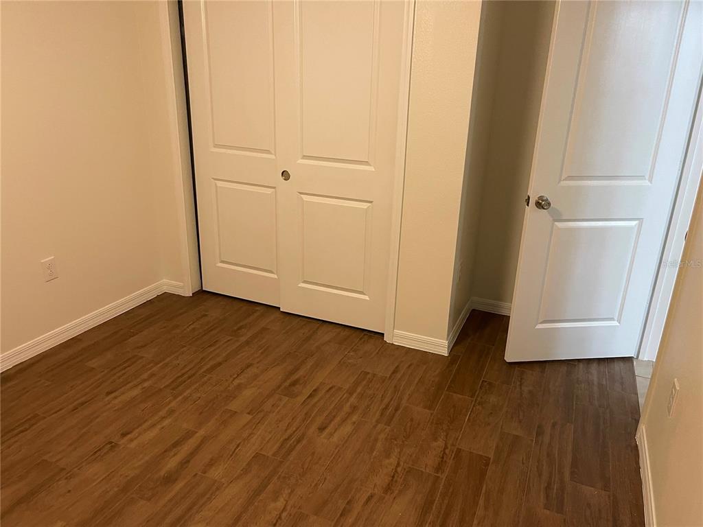 A room with wood-look tile flooring, a white closet, and an open doorway — 3063 SANCTUARY, CLERMONT, FL