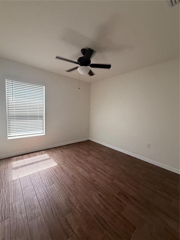 An empty bedroom features wood-look tile flooring, white walls, and a ceiling fan — 3063 SANCTUARY, CLERMONT, FL