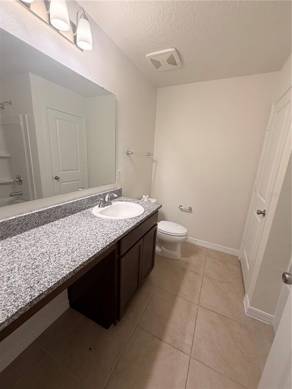 A bathroom features a granite vanity, a single sink, a toilet, and tile flooring — 3063 SANCTUARY, CLERMONT, FL