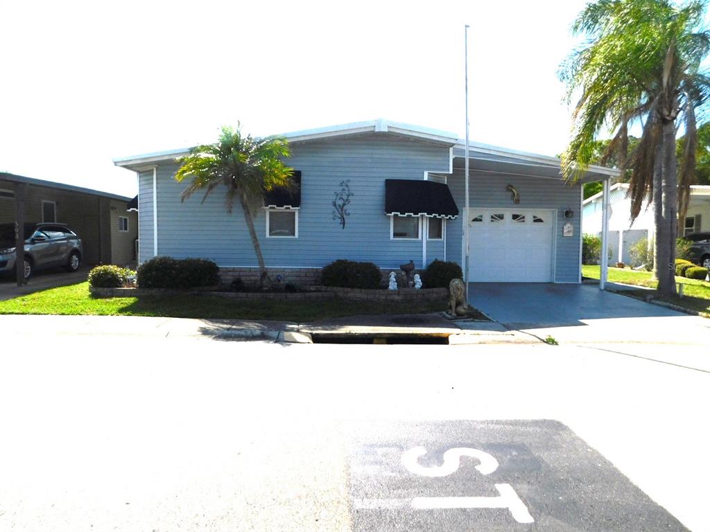 A light blue single-story house features a carport, a garage door, and a palm tree — 1001 STARKEY ROAD UNIT 395, LARGO, FL