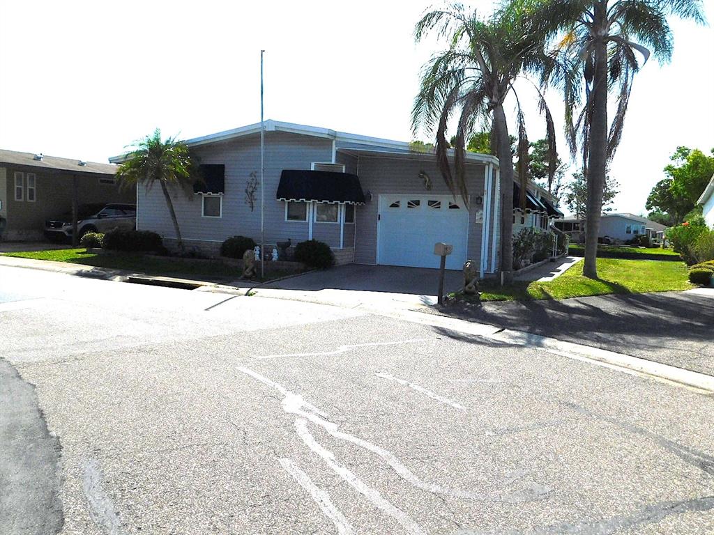 A light gray manufactured home features a white garage door and two tall palm trees — 1001 STARKEY ROAD UNIT 395, LARGO, FL