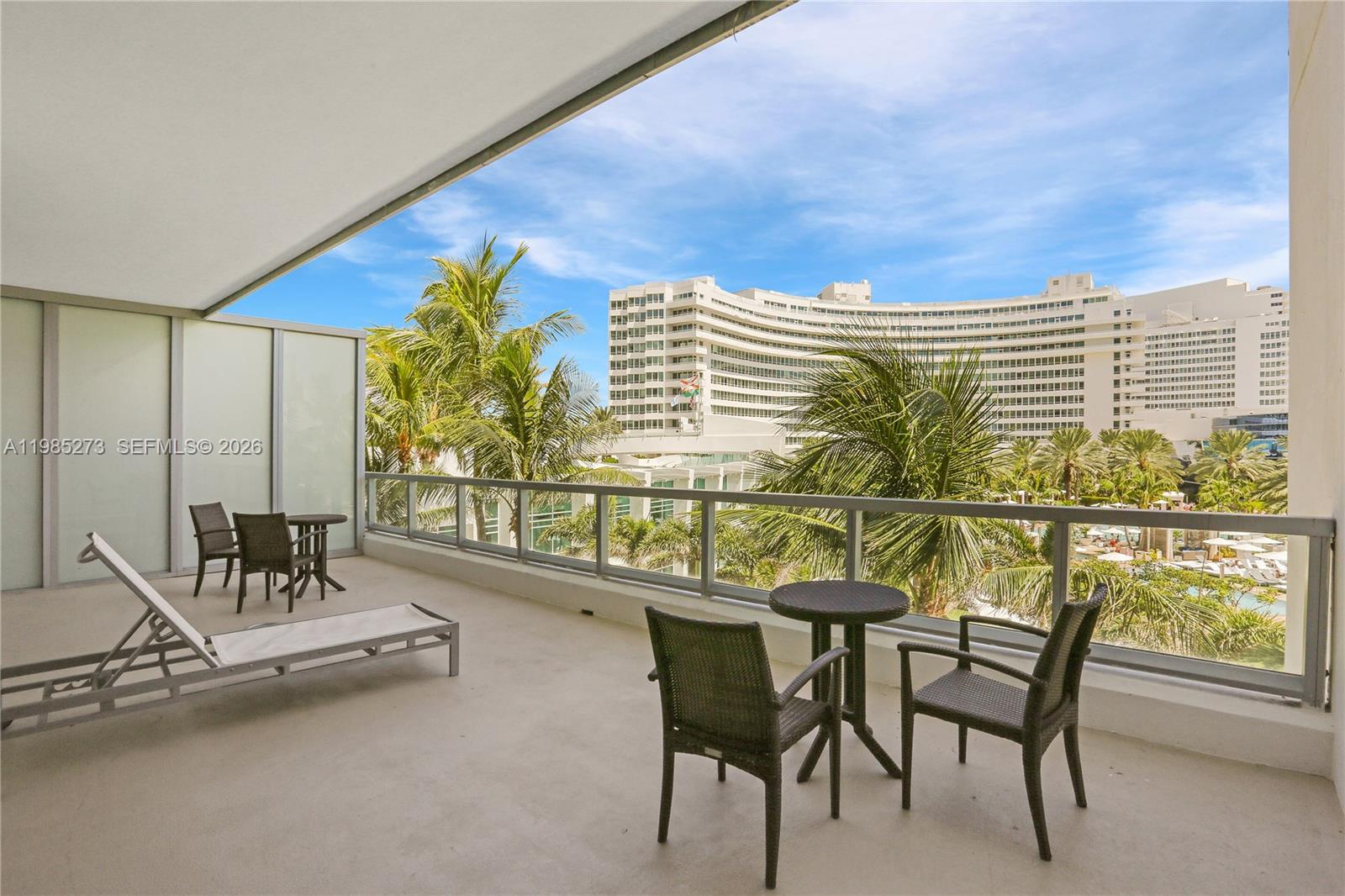 A balcony features outdoor furniture, a glass railing, and views of a large resort building — 4391 Collins Ave # 307, Miami Beach FL 33140, MIAMI BEACH, FL