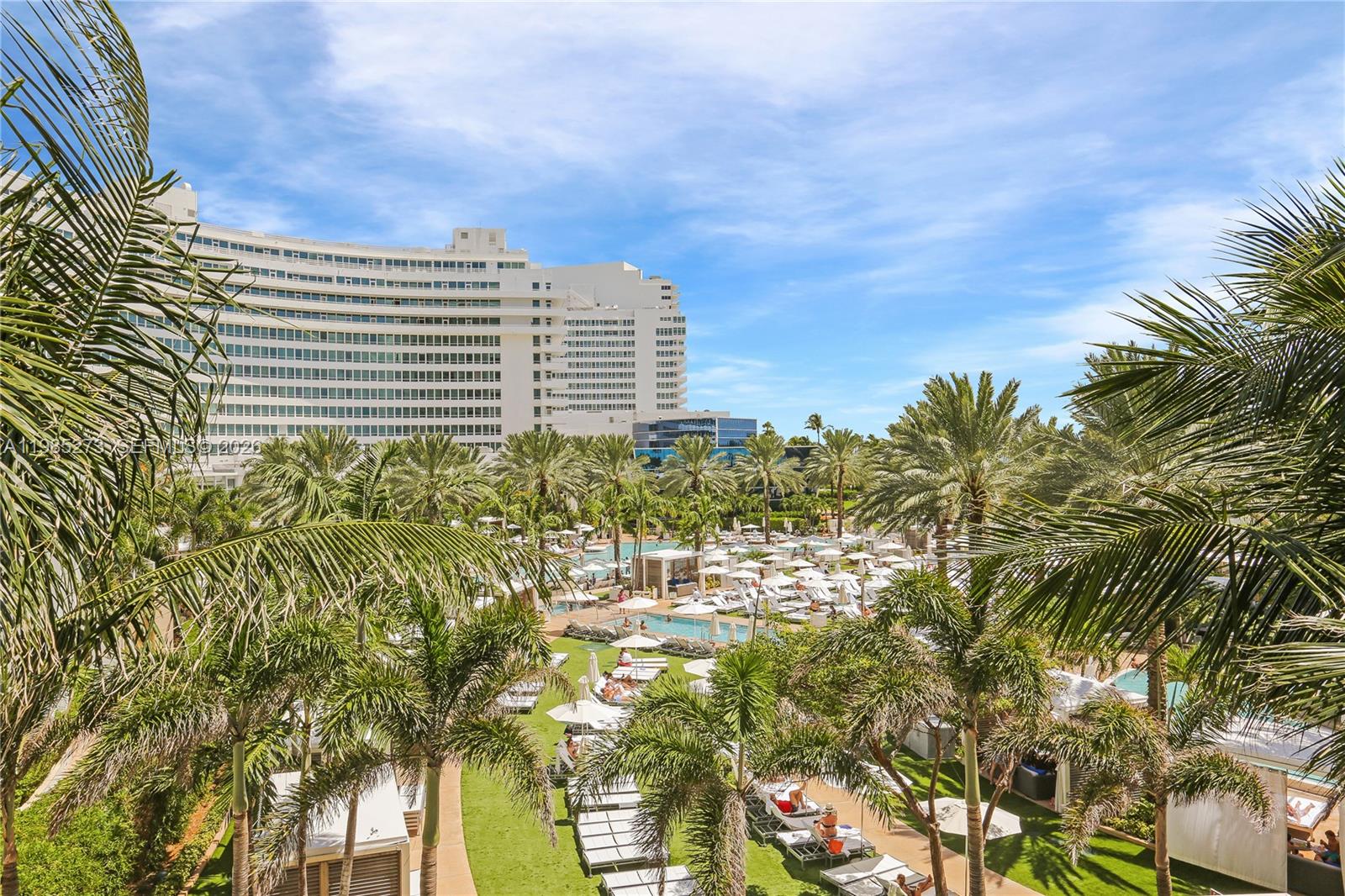A high-angle view shows a resort pool area surrounded by palm trees and a hotel — 4391 Collins Ave # 307, Miami Beach FL 33140, MIAMI BEACH, FL