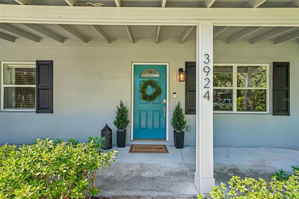 A teal front door with a wreath sits on a porch with two potted plants — 3924 W BAY VIEW AVENUE, TAMPA, FL