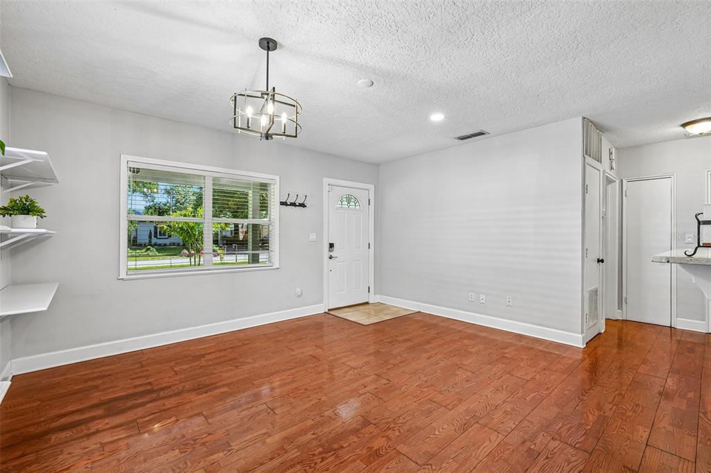 A living room with hardwood floors, a white front door, and a modern chandelier — 3924 W BAY VIEW AVENUE, TAMPA, FL
