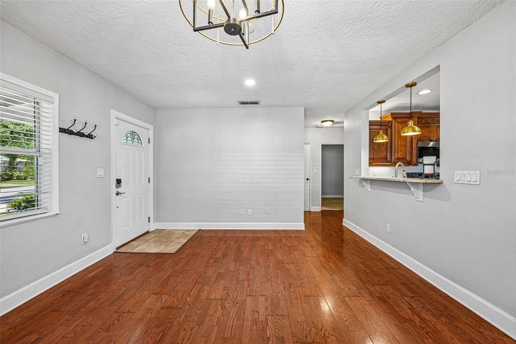 An interior view of an entryway with hardwood floors, a white front door, and kitchen pass-through — 3924 W BAY VIEW AVENUE, TAMPA, FL