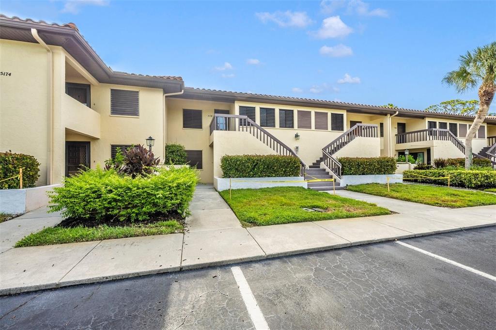 A two-story apartment building with beige stucco walls, brown tile roofs, and exterior staircases — 5178 LAKE VILLAGE DRIVE UNIT 86, SARASOTA, FL