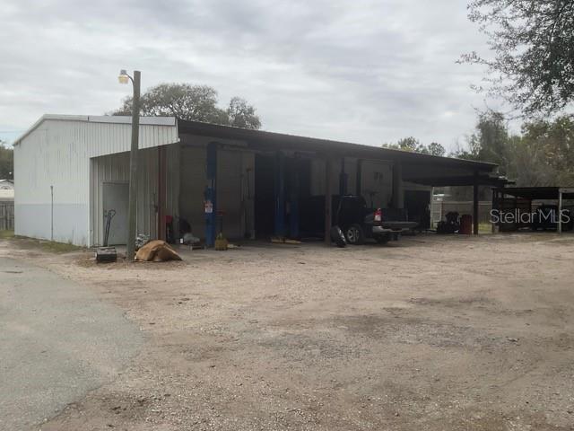 A metal-sided commercial garage building with open bays and a gravel lot — 32416 COUNTY ROAD 473, LEESBURG, FL