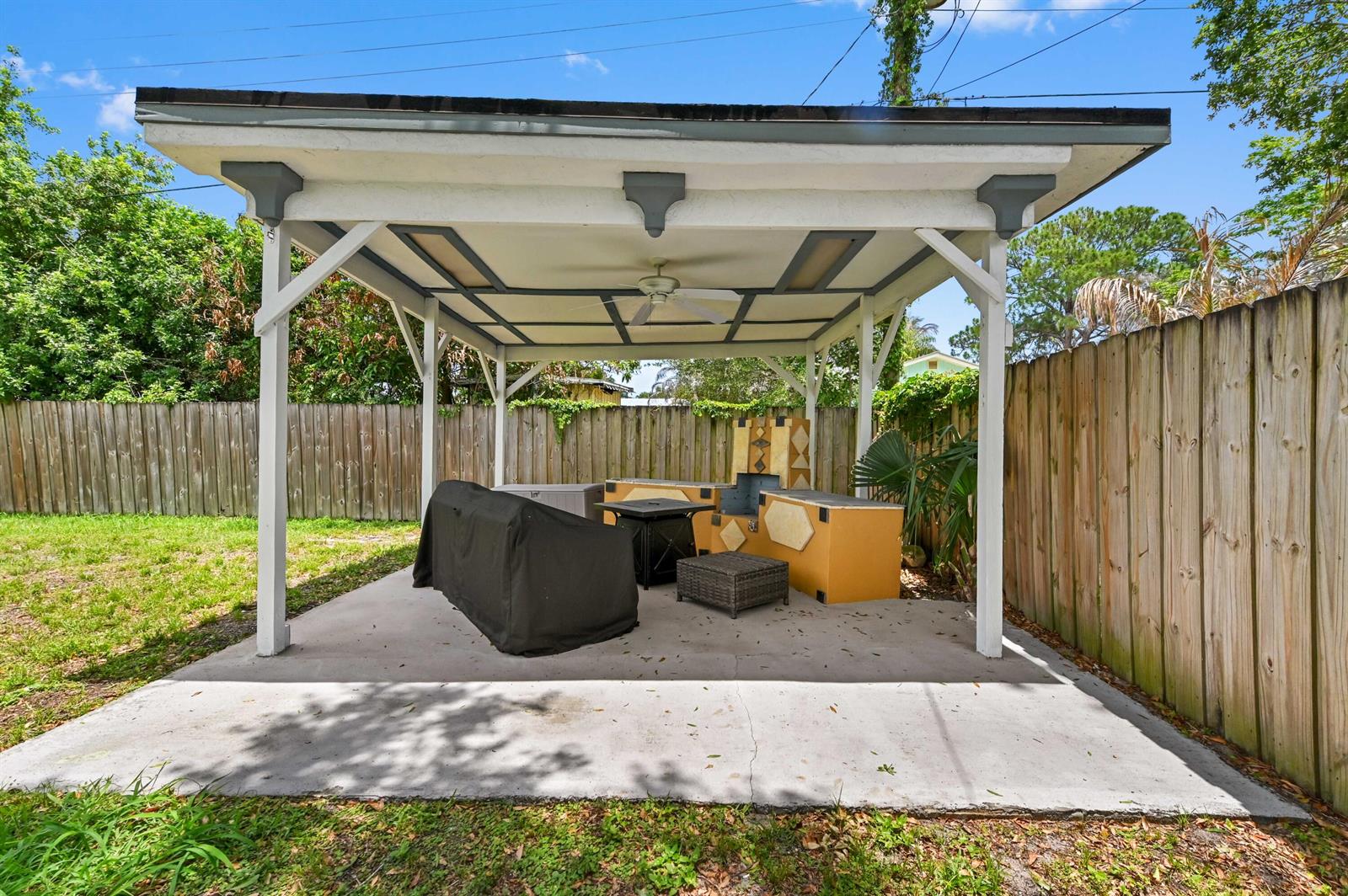 A covered outdoor patio features a concrete floor, a ceiling fan, and a built-in grill — 5709 SE Indigo Avenue, Stuart FL 34997, STUART, FL