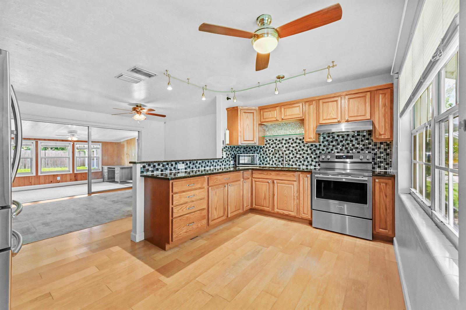 A kitchen with wood cabinets, stainless steel appliances, and a mosaic tile backsplash — 5709 SE Indigo Avenue, Stuart FL 34997, STUART, FL
