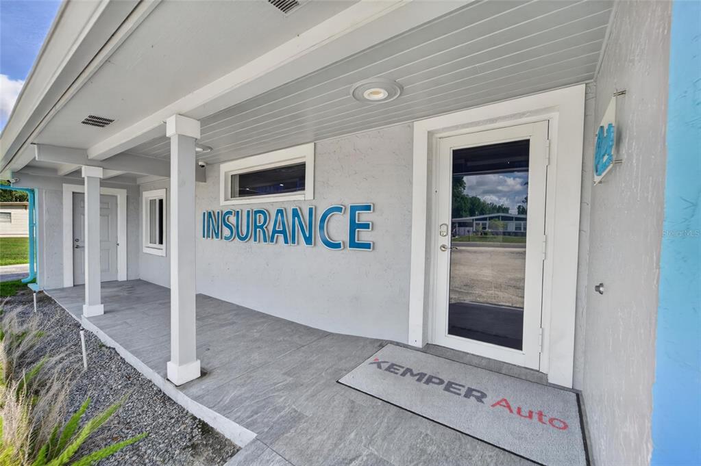 The exterior of a commercial building features a covered porch, an insurance sign, and a door — 1233 BARTOW ROAD, LAKELAND, FL
