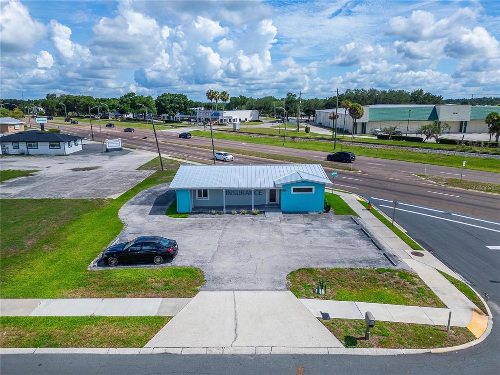 An aerial view shows a turquoise commercial building with a metal roof and parking lot — 1233 BARTOW ROAD, LAKELAND, FL