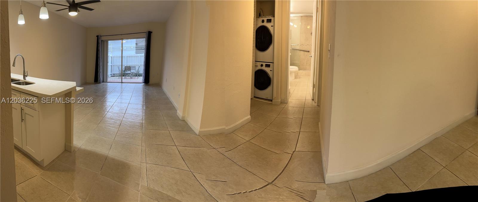 A kitchen area with tile flooring leads to a sliding glass door and laundry closet — 10900 SW 104th St # 118, Miami FL 33176, MIAMI, FL