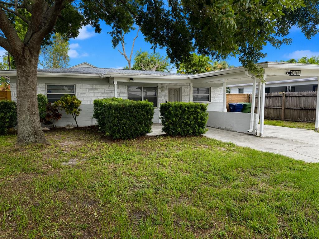 A single-story house with a white stone facade, a carport, and a front lawn — 4314 W CARMEN STREET, TAMPA, FL