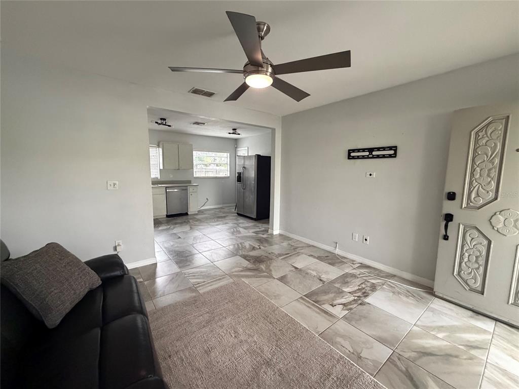 A living room with tile flooring and a ceiling fan opens into a kitchen area — 4314 W CARMEN STREET, TAMPA, FL
