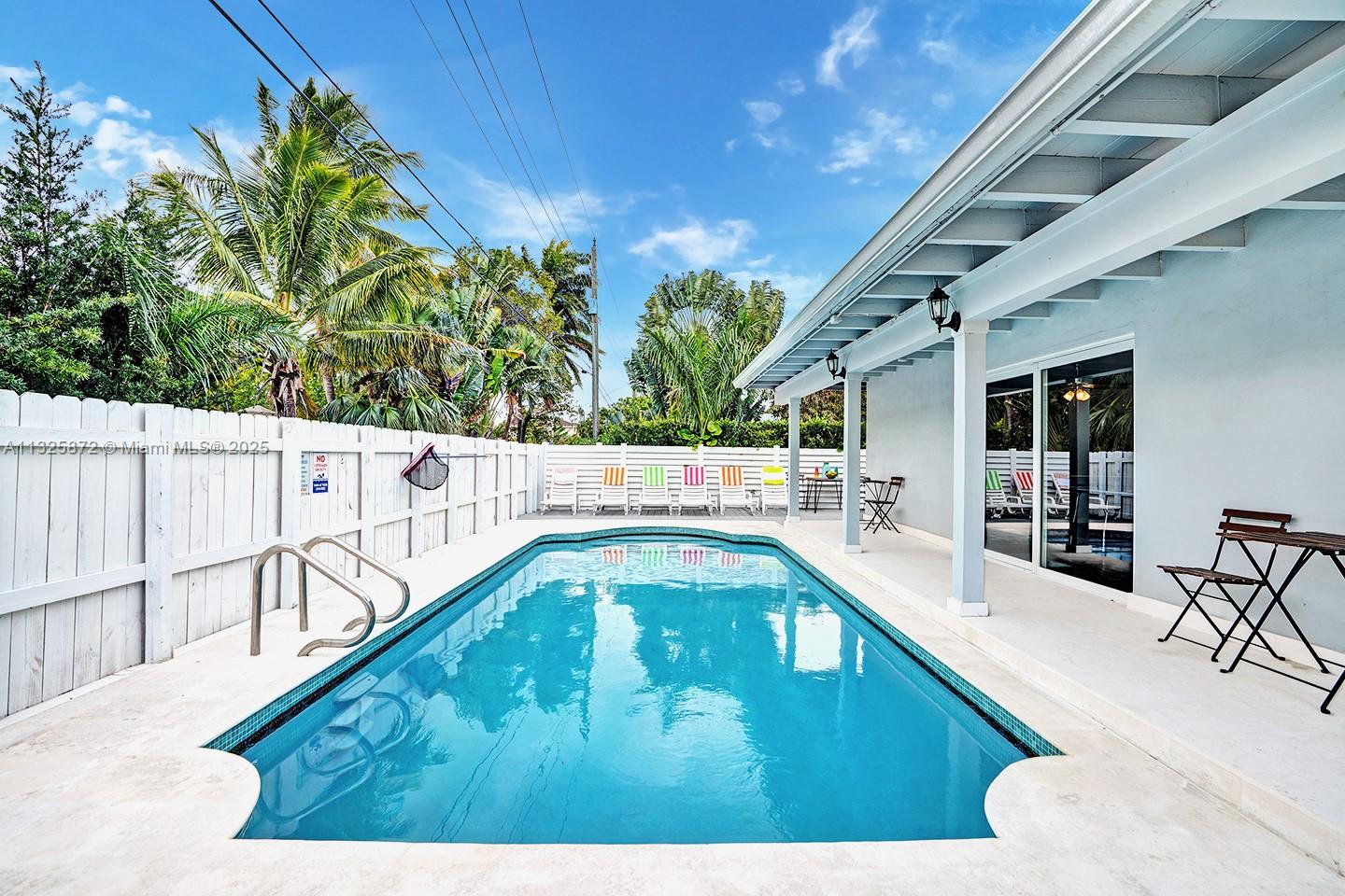 A rectangular swimming pool sits on a patio next to a house with a porch — 1018 Adams St, Hollywood FL 33019, HOLLYWOOD, FL