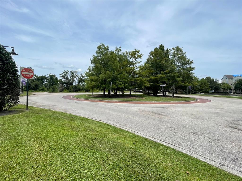 A paved roundabout features a central grassy island with several trees under a blue sky — Parcel 2 - 607 OVIEDO BLVD, OVIEDO, FL