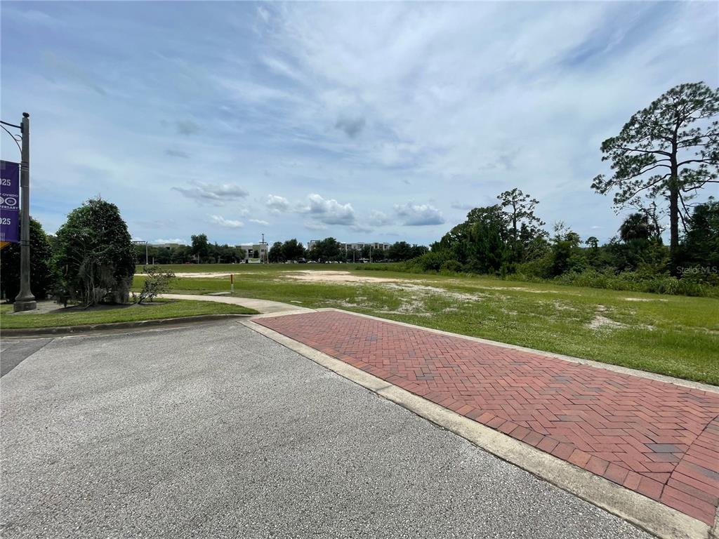 A paved driveway leads to an open, grassy vacant lot under a cloudy sky — Parcel 2 - 607 OVIEDO BLVD, OVIEDO, FL