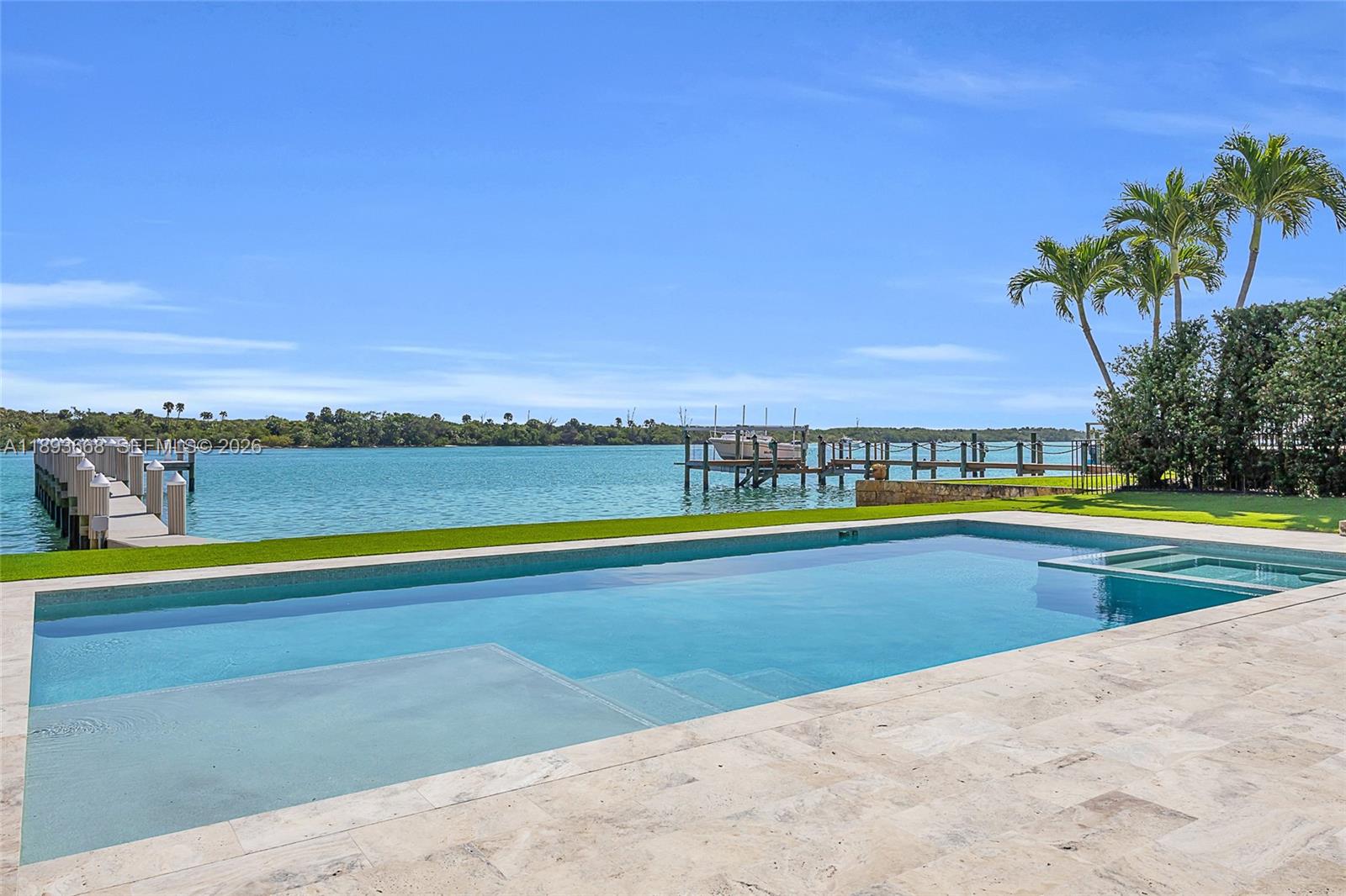A swimming pool overlooks a waterfront dock and palm trees under a clear blue sky — 18119 SE Federal Hwy, Jupiter FL 33469, JUPITER, FL