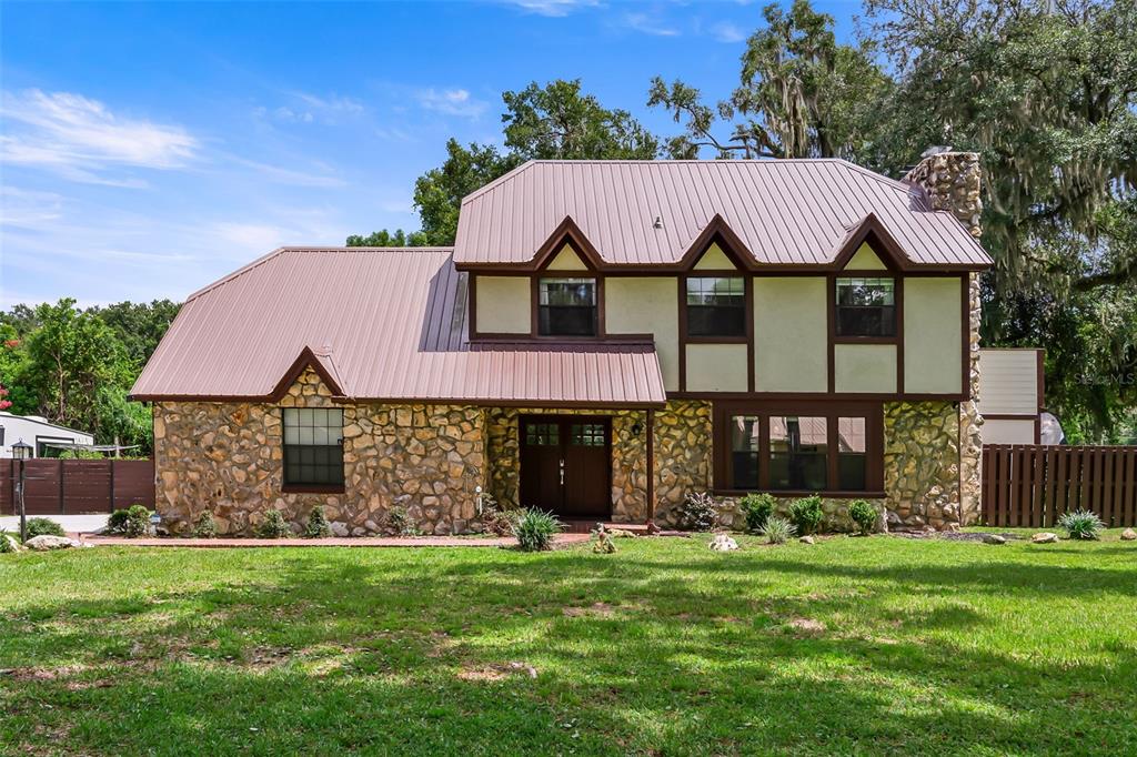 A two-story house with a stone facade, brown trim, and a metal roof — 102 THICKET LANE, PALATKA, FL