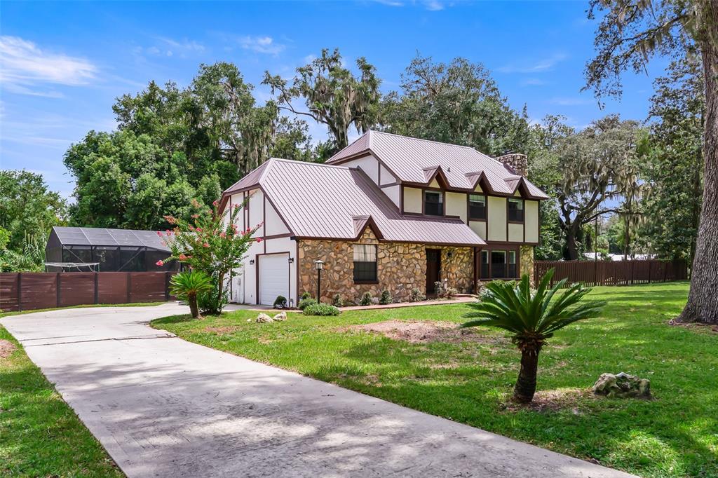 A two-story house with a stone facade, metal roof, and a concrete driveway — 102 THICKET LANE, PALATKA, FL