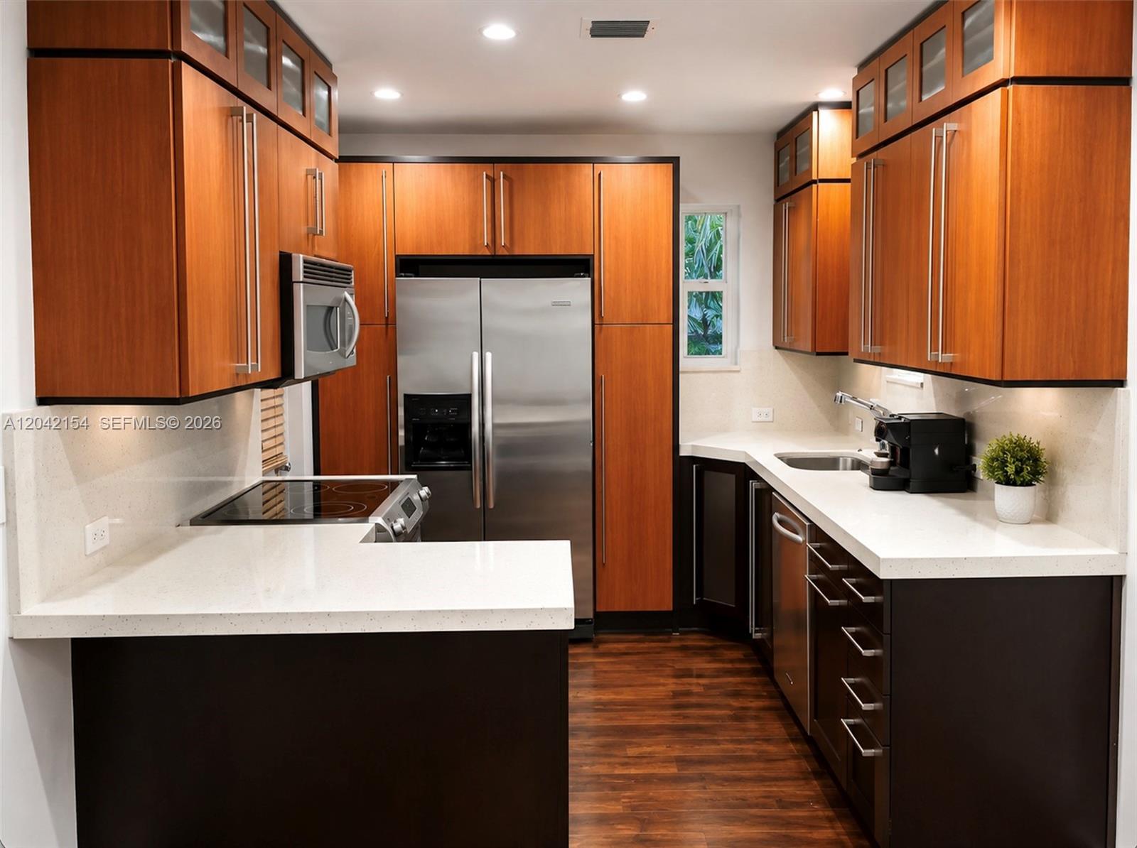 A kitchen features wood-toned upper cabinets, dark lower cabinets, stainless steel appliances, and white countertops — 3612 SW 1st Ave, Miami FL 33145, MIAMI, FL