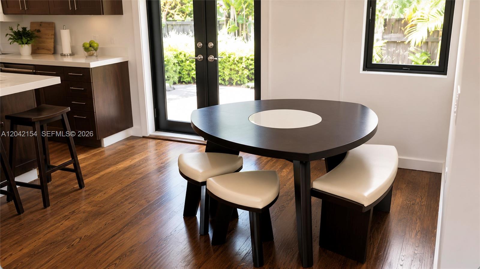 A modern kitchen features dark wood cabinetry, a triangular dining table, and hardwood floors — 3612 SW 1st Ave, Miami FL 33145, MIAMI, FL