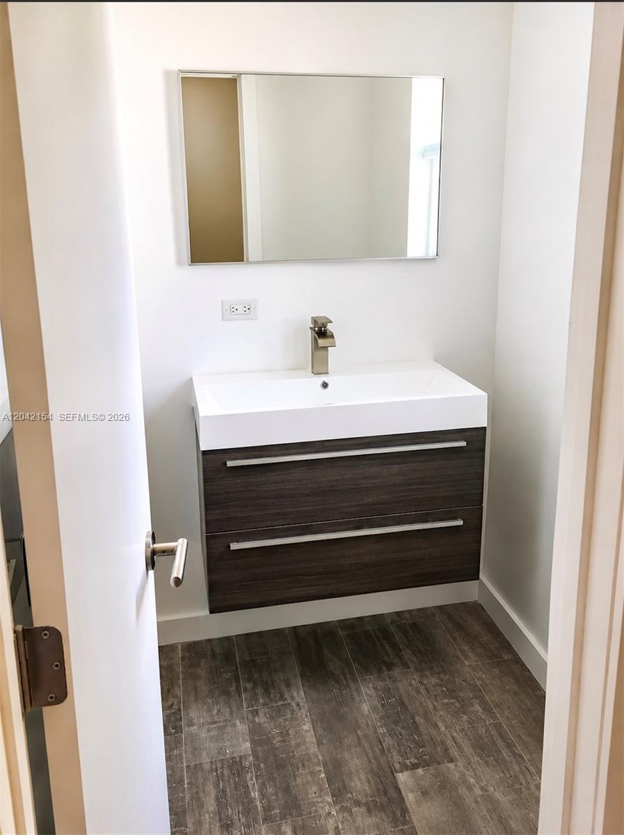 A modern bathroom features a floating dark wood vanity, a white sink, and a rectangular mirror — 3612 SW 1st Ave, Miami FL 33145, MIAMI, FL
